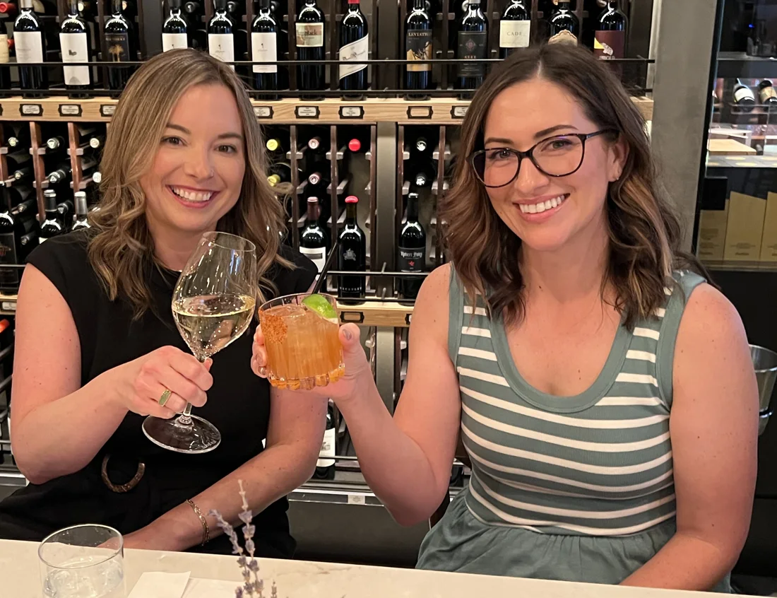 Erin and Ashley raising a toast at a restaurant